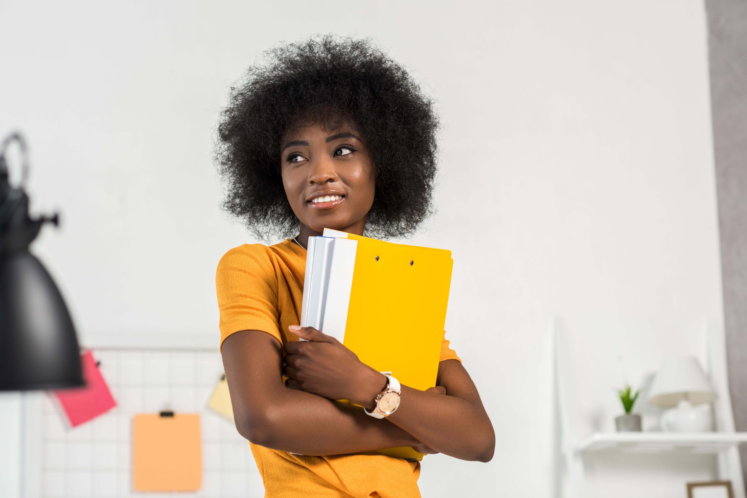 portrait of young smiling freelancer with folders in hands at home